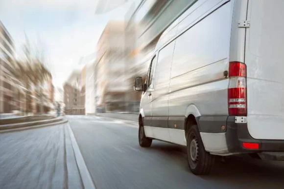 Weißer Transporter fährt durch die Stadt.